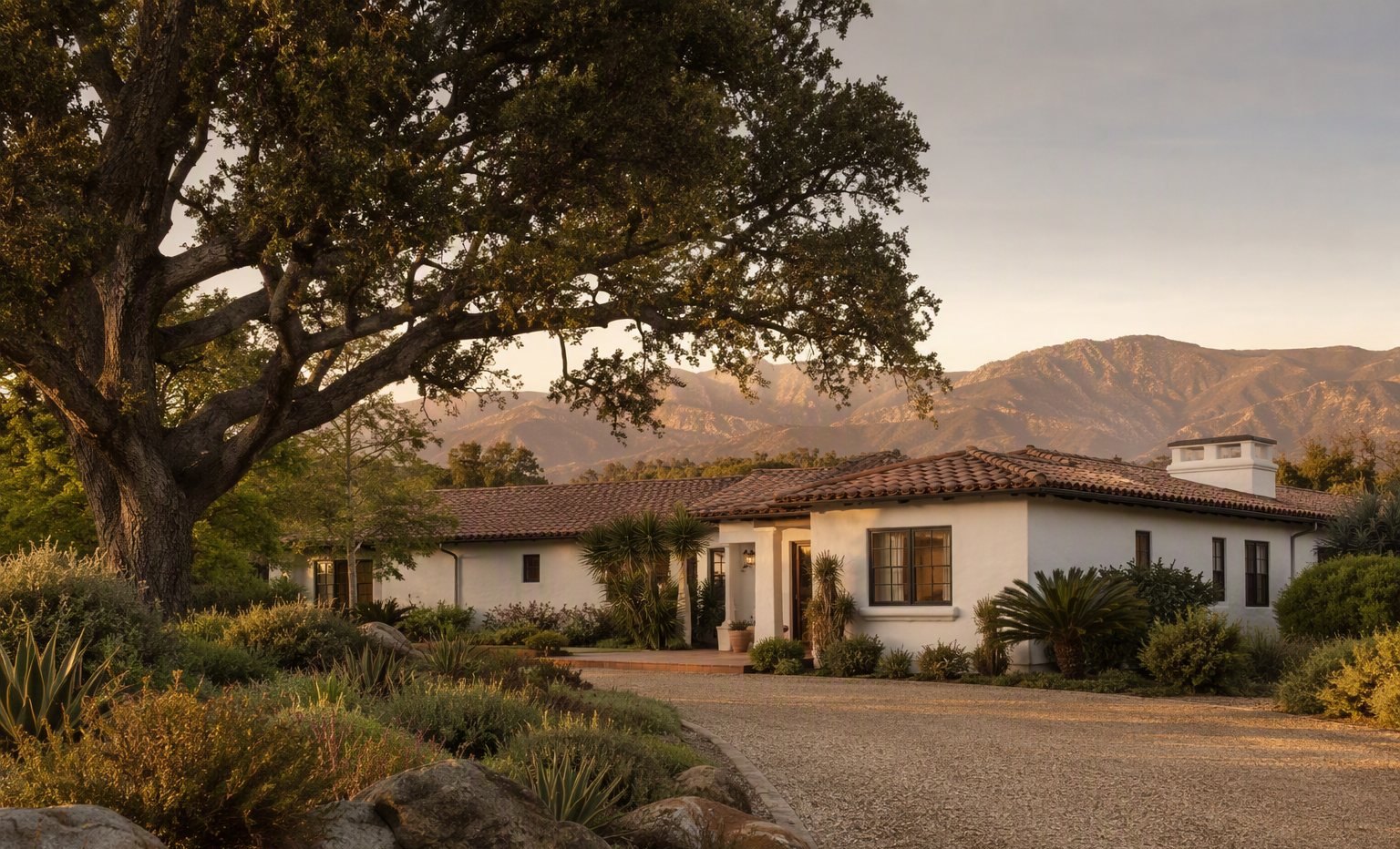 A single-story California ranch house on a large parcel beneath mature oaks
